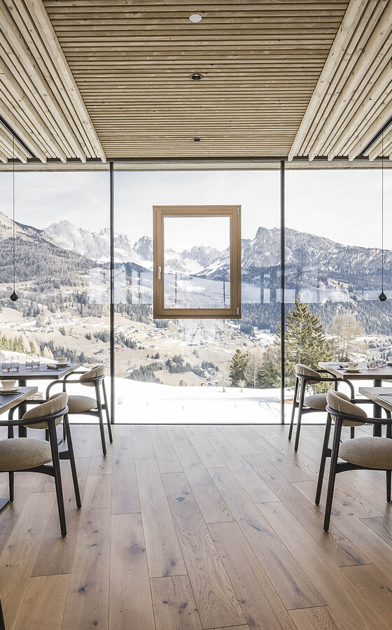 Heller Speiseraum im Hotel Cendevaves mit Holztischen, gepolsterten Sitzbänken und Panoramablick auf die Berglandschaft.